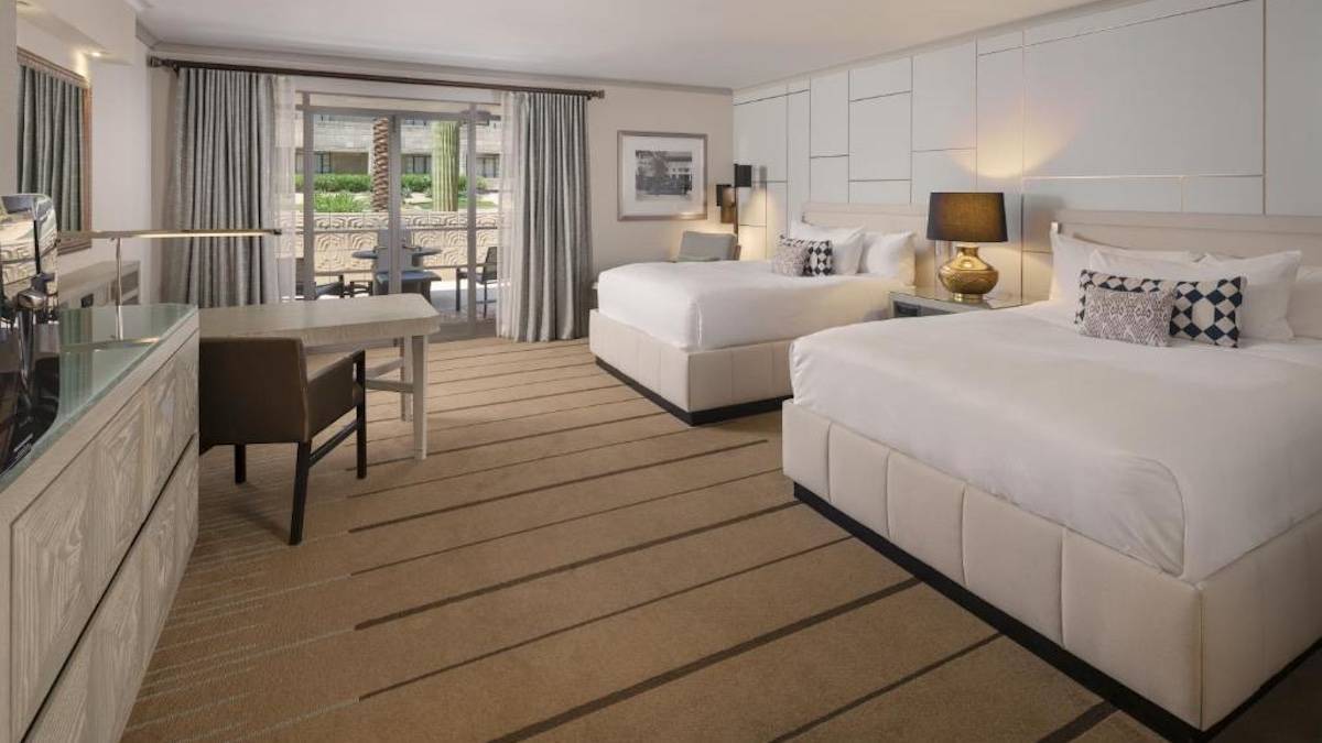 White walled hotel room with two white beds and white furniture